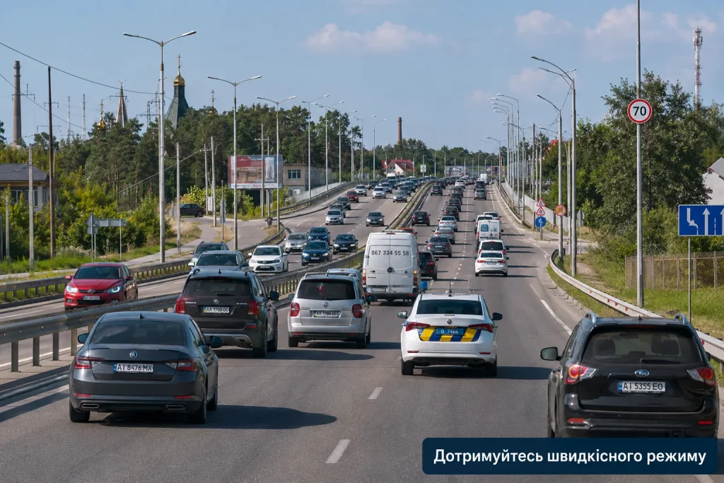 поток автомобилей на дороге Киева и патрульный автомобиль без заметных внешних отличий
